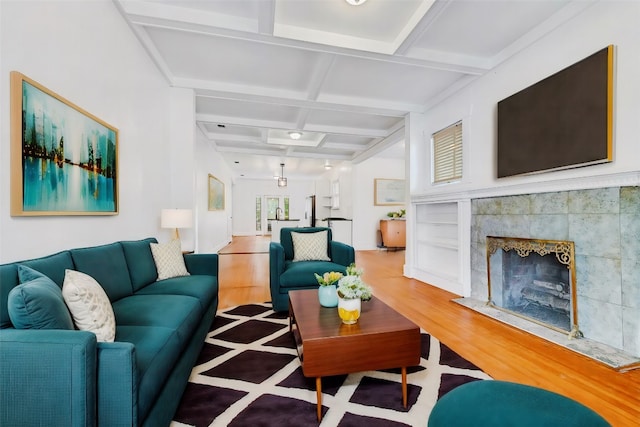 living room with coffered ceiling, beamed ceiling, hardwood / wood-style flooring, and a fireplace