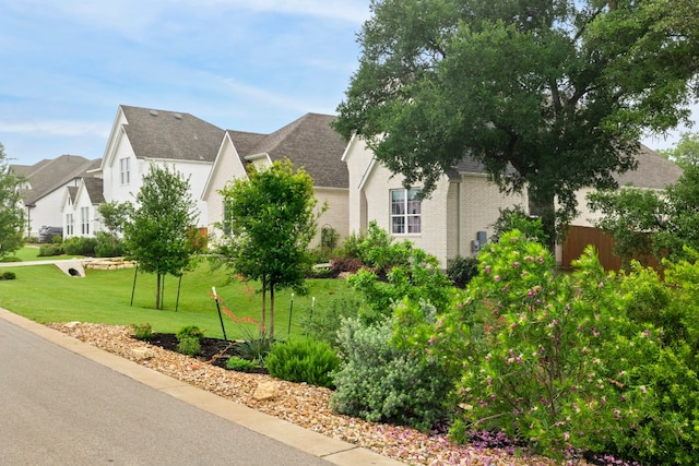 view of side of property featuring a residential view, roof with shingles, fence, a yard, and brick siding