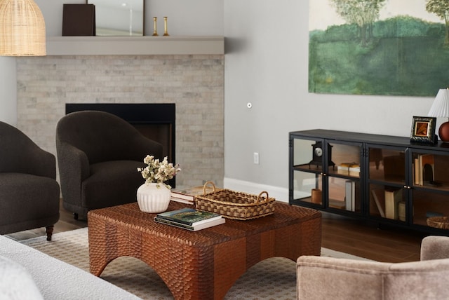 living room with a fireplace, baseboards, and wood finished floors