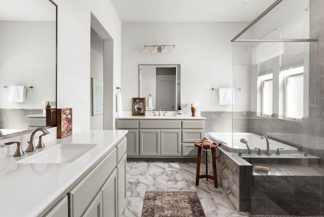 bathroom featuring marble finish floor, two vanities, a sink, and a bath