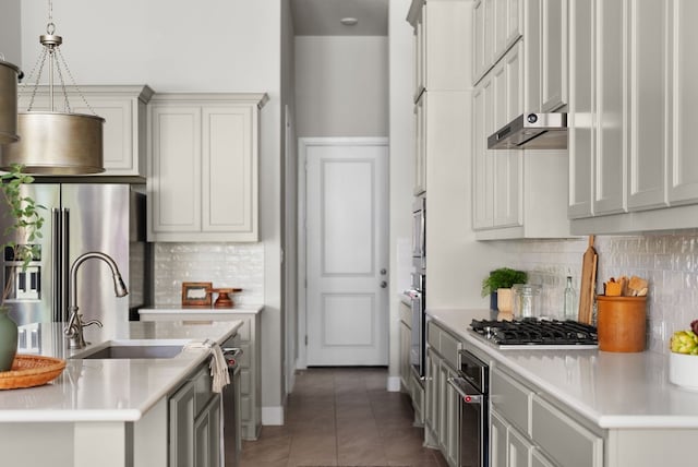 kitchen with dark tile patterned flooring, decorative light fixtures, stainless steel appliances, light countertops, and under cabinet range hood