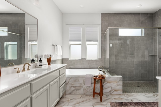 full bathroom featuring marble finish floor, a garden tub, a wealth of natural light, and a stall shower