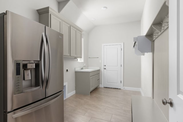 kitchen with light countertops, stainless steel fridge, lofted ceiling, and gray cabinetry