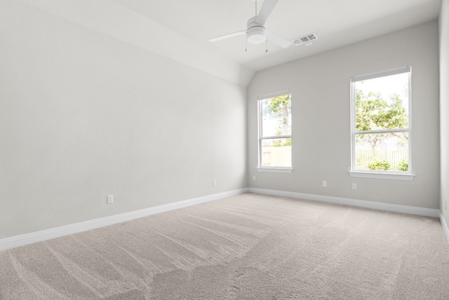 spare room featuring light carpet, baseboards, visible vents, a ceiling fan, and vaulted ceiling