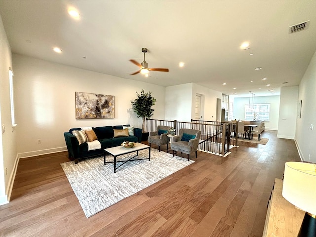 living area with recessed lighting, visible vents, a ceiling fan, wood finished floors, and baseboards