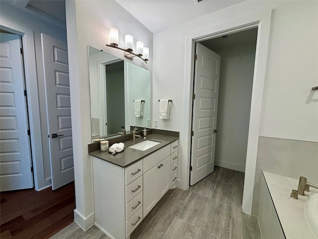 full bathroom featuring vanity, baseboards, and wood finished floors