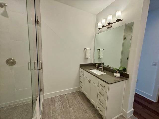 full bathroom with a stall shower, vanity, and baseboards