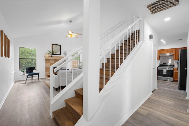 staircase featuring ceiling fan, vaulted ceiling, and hardwood / wood-style floors