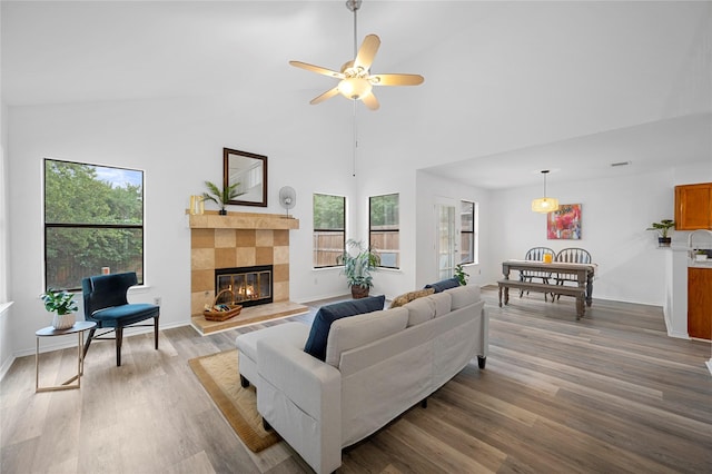 living room with ceiling fan, plenty of natural light, hardwood / wood-style floors, and a tiled fireplace