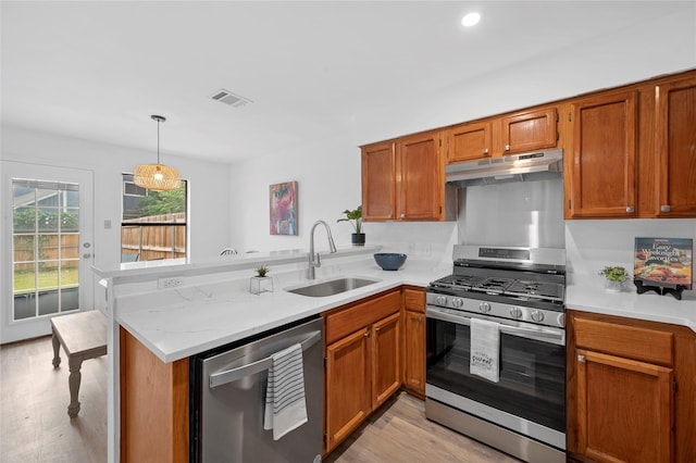 kitchen with sink, hanging light fixtures, light hardwood / wood-style flooring, appliances with stainless steel finishes, and kitchen peninsula