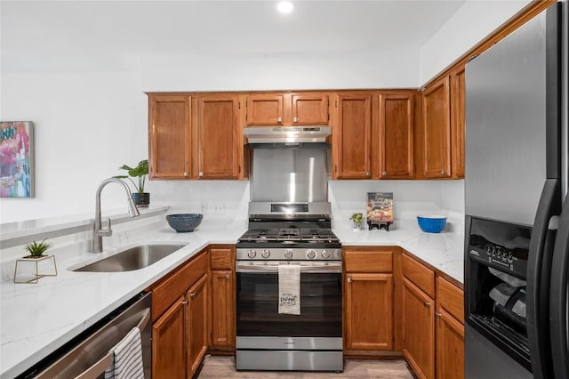 kitchen featuring light stone countertops, appliances with stainless steel finishes, kitchen peninsula, and sink