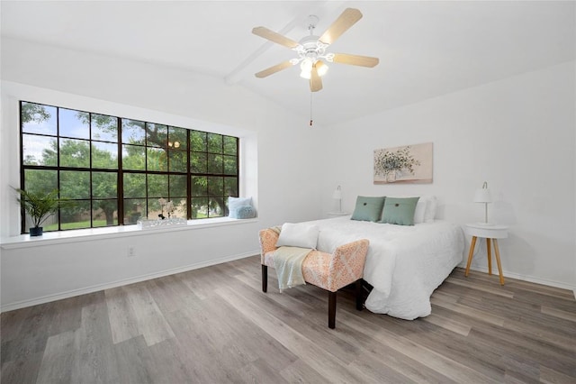 bedroom featuring ceiling fan, hardwood / wood-style floors, and lofted ceiling with beams