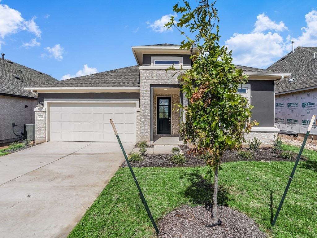 prairie-style home with a front yard and a garage