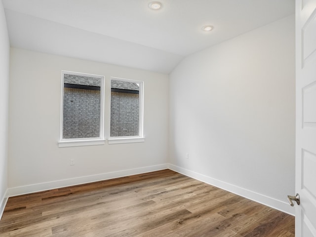 empty room with light hardwood / wood-style floors and lofted ceiling