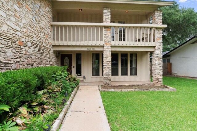 property entrance with a balcony and a lawn