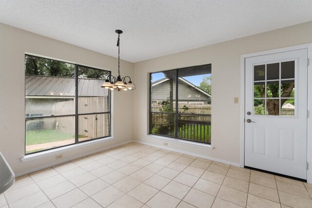 unfurnished dining area featuring a textured ceiling, a notable chandelier, and light tile patterned flooring