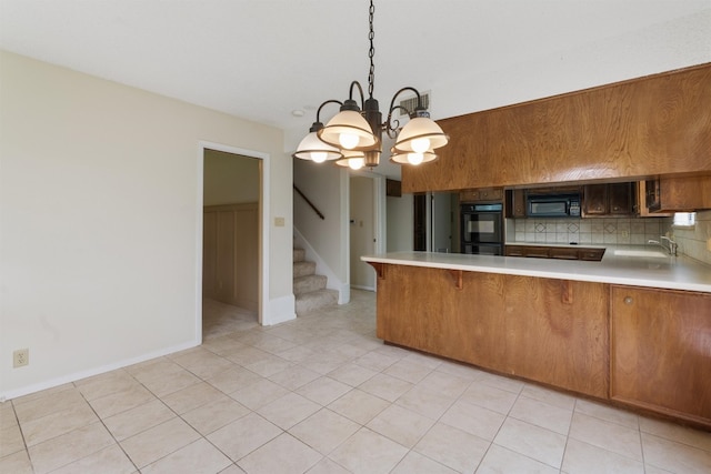 kitchen with decorative backsplash, a kitchen bar, black appliances, kitchen peninsula, and a notable chandelier