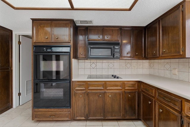 kitchen featuring light tile patterned flooring, tasteful backsplash, a textured ceiling, and black appliances