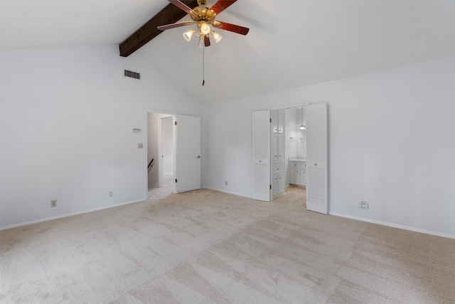 unfurnished bedroom with light colored carpet, ensuite bathroom, beamed ceiling, and ceiling fan