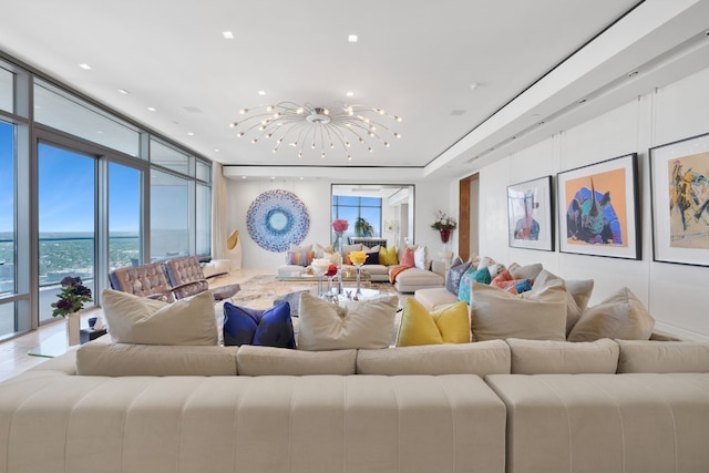 living room with an inviting chandelier, a water view, and a wall of windows