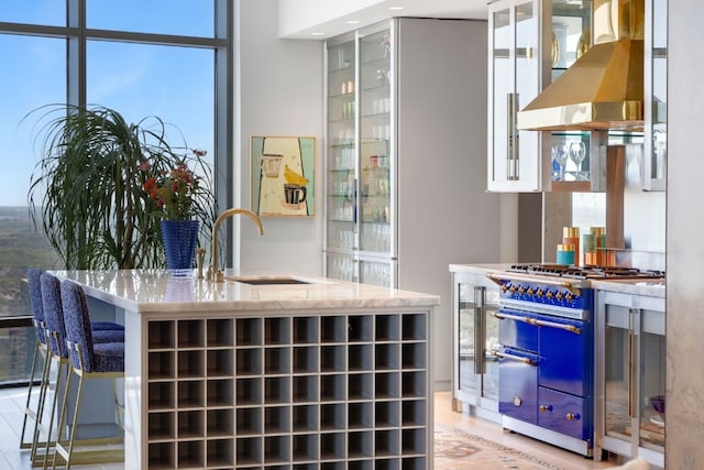 interior space with double oven range, wall chimney exhaust hood, white cabinetry, and a wealth of natural light