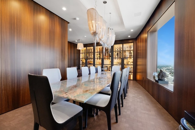 dining space featuring wooden walls and a notable chandelier