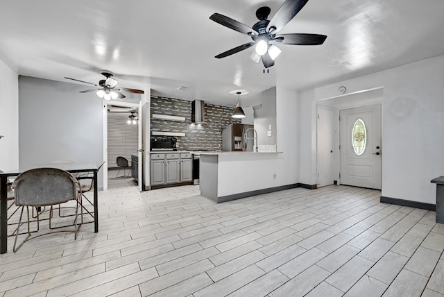 kitchen with wall chimney exhaust hood, stainless steel refrigerator with ice dispenser, backsplash, light hardwood / wood-style floors, and ceiling fan