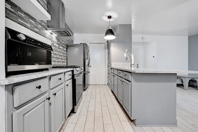 kitchen with stainless steel gas range, backsplash, decorative light fixtures, and gray cabinetry