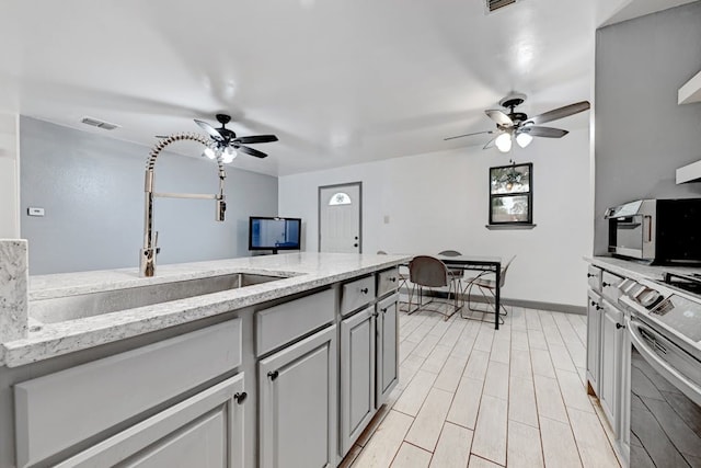 kitchen with ceiling fan, gray cabinetry, stainless steel electric range, and light stone countertops