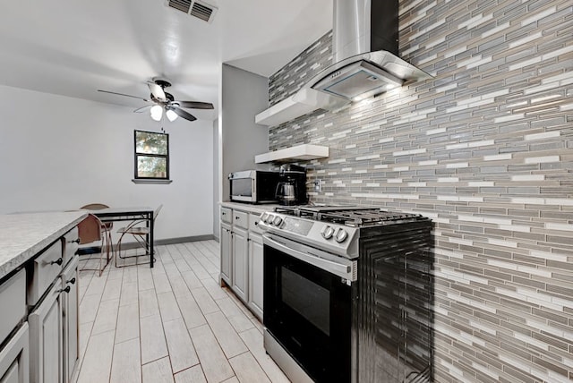 kitchen with backsplash, appliances with stainless steel finishes, wall chimney exhaust hood, and ceiling fan