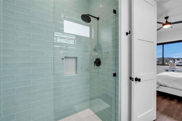 ensuite bathroom with connected bathroom, tiled shower, and wood finished floors