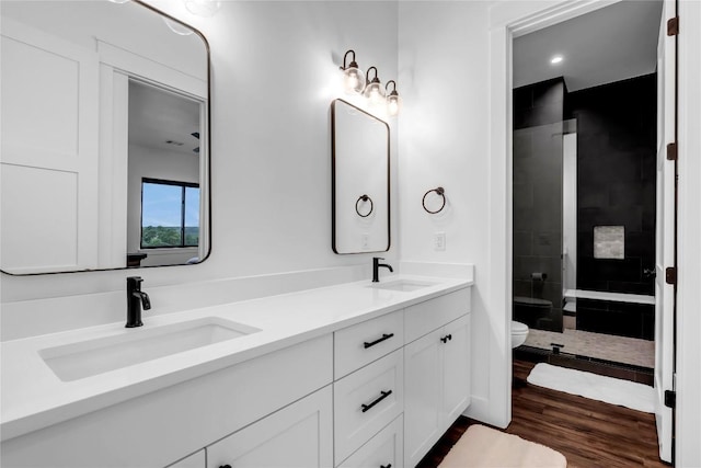 full bath featuring toilet, a shower stall, double vanity, and a sink