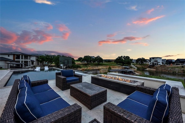 view of patio with an outdoor living space with a fire pit and a water view