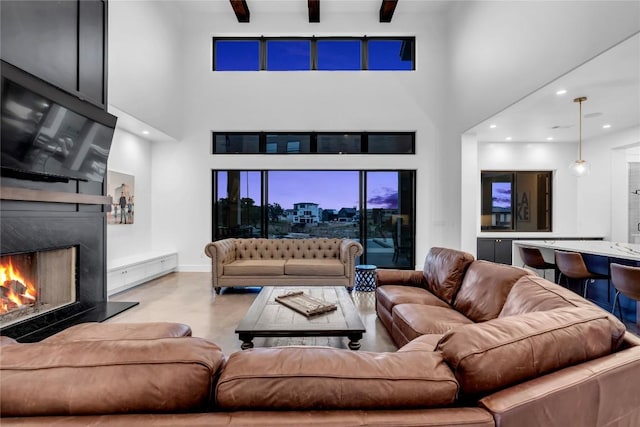 living room with a premium fireplace, finished concrete floors, a high ceiling, beam ceiling, and recessed lighting