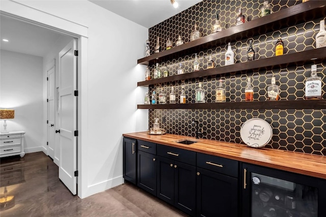 bar with finished concrete floors, indoor wet bar, backsplash, and baseboards