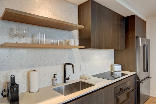 kitchen with high end fridge, sink, tasteful backsplash, wall oven, and black electric stovetop