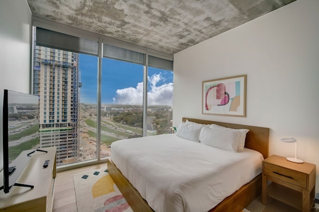 bedroom with a wall of windows and hardwood / wood-style flooring