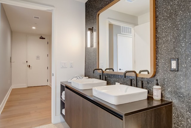 bathroom with double vanity, hardwood / wood-style flooring, and tasteful backsplash