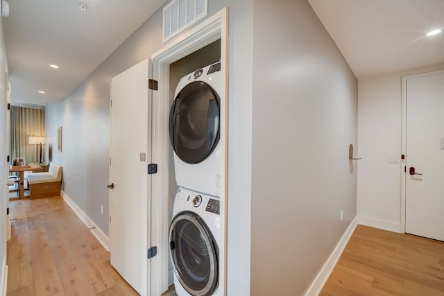 washroom with light hardwood / wood-style floors and stacked washer and clothes dryer