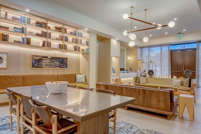 kitchen with light hardwood / wood-style flooring, a chandelier, kitchen peninsula, hanging light fixtures, and elevator