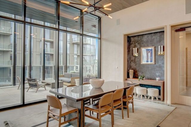 dining room with light tile patterned flooring, a high ceiling, a notable chandelier, and a wall of windows