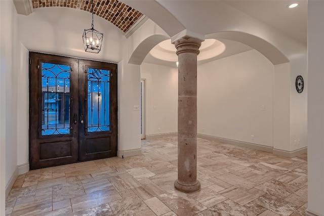 foyer featuring decorative columns, a towering ceiling, a chandelier, and french doors