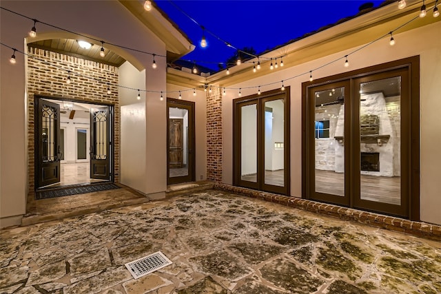 exterior space with french doors, beamed ceiling, and brick wall