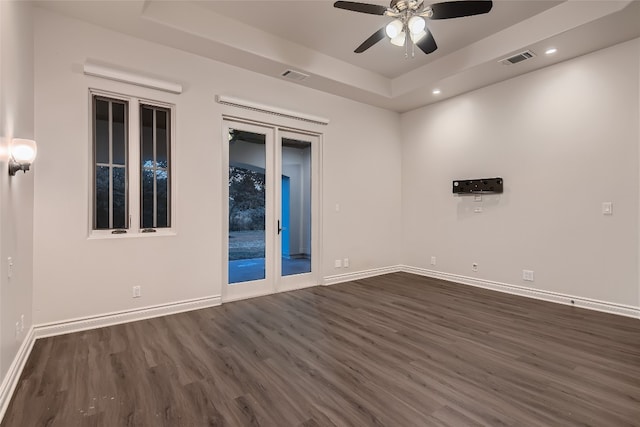 unfurnished room featuring a tray ceiling, ceiling fan, and dark hardwood / wood-style floors