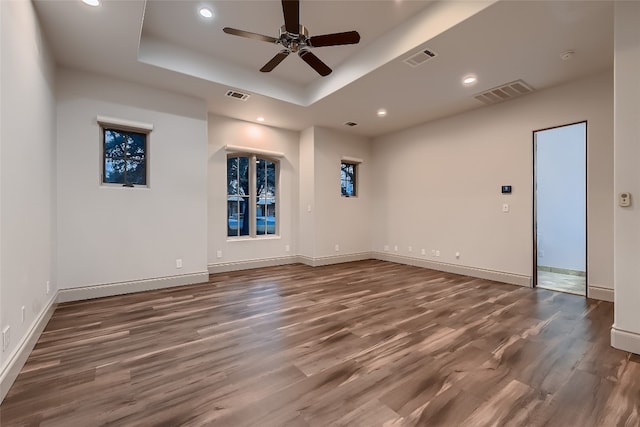 spare room with ceiling fan, a raised ceiling, and dark wood-type flooring