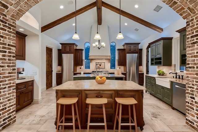 kitchen with pendant lighting, beam ceiling, a kitchen island, backsplash, and appliances with stainless steel finishes