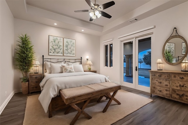 bedroom with a tray ceiling, dark hardwood / wood-style flooring, ceiling fan, and access to exterior