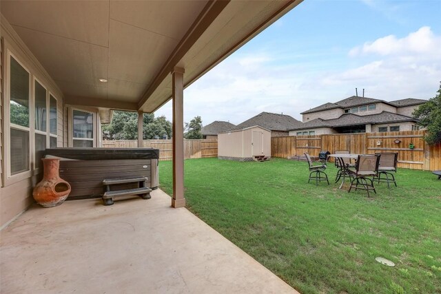 view of yard featuring a hot tub, a storage unit, and a patio area