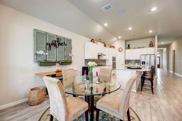 dining space featuring sink and lofted ceiling