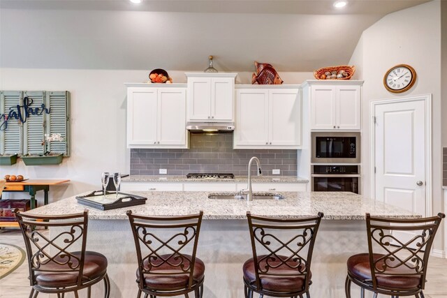 kitchen featuring a kitchen bar, white cabinetry, sink, and appliances with stainless steel finishes